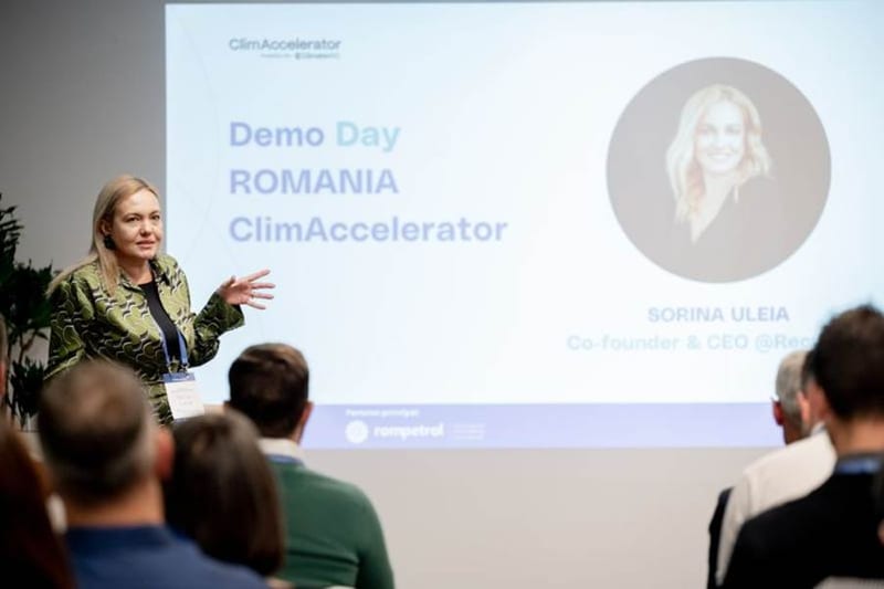Speaker presenting at Romania ClimAccelerator Demo Day beside a slide naming Sorina Uleia, Co-founder and CEO
