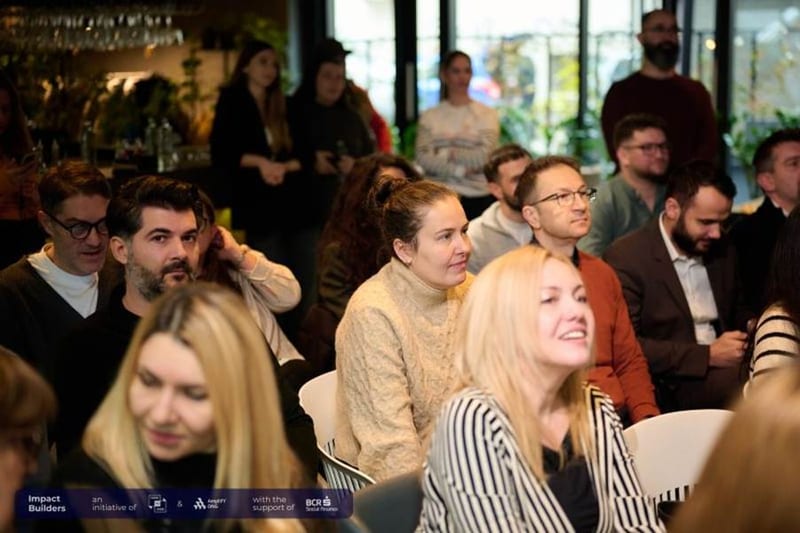 Audience seated and listening at the Impact Builders meetup, with a banner crediting BCR Social Finance support