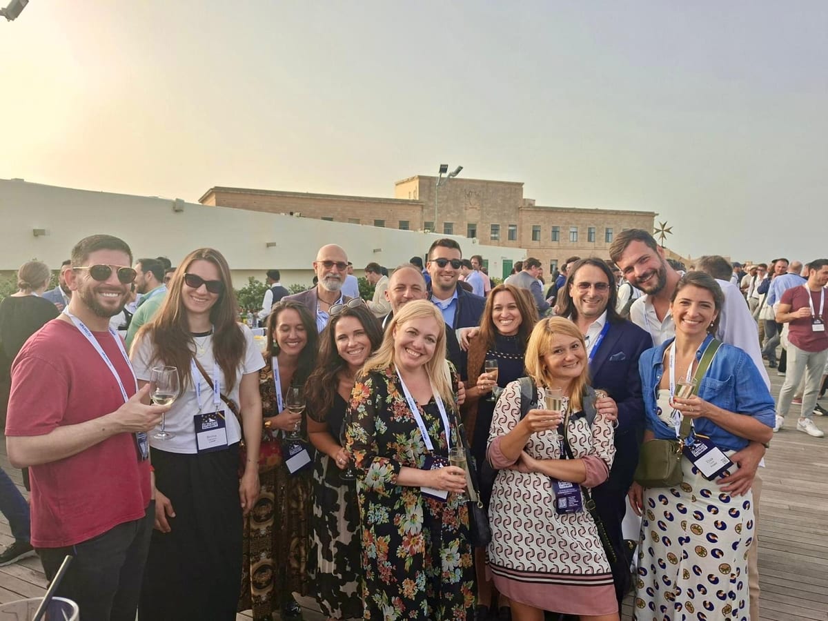 Group of attendees with lanyards posing on a rooftop terrace at sunset during the EU-Startups Summit 2026 in Valletta